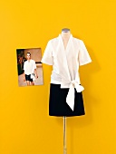 White blouse and black skirt on mannequin against yellow wall