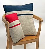Two knitted pillows in with blue and red stripes on wooden chair