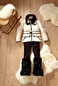 White down jacket, pants and faux fur boots on wooden floor