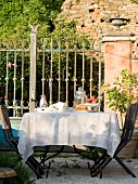 Oak dining table with chairs and cutlery outside Tuscan country house