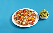 Pizza on plate and bowl of grapes on blue background