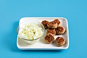 Bowl of coleslaw with mini burgers on white dish