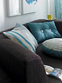 Pillow in turquoise colour on brown couch
