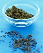Bowl of cumin paste and cumin seeds on blue background