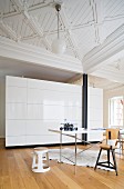 A spacious living room in a period building with a coffered ceiling and a cupboard as a room divider