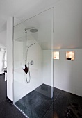 Interior of shower under slope roof with transparent glass dividing wall