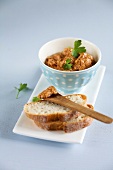 Bowl of peanut spread and slice of bread on plate