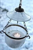 Lit candle in glass, hanging