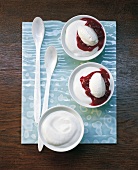 Mousse of buttermilk with red fruit sauce in bowls with spoon on tray