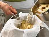 Apple soup being passed through sieve with cloth, step 3