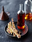A bottle of caramel syrup and sesame brittle with cranberries