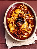 Wild boar ragout with armagnac prunes and noodles in serving dish