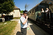 People on train and station master whistling in Franconian Switzerland, Bavaria, Germany