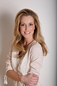 Portrait of pretty blonde woman wearing beige blouse, smiling