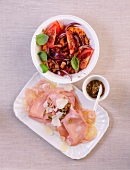 Red lentil salad in bowl with mortadella and carpaccio on plate