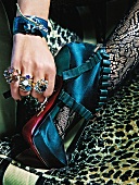 Close-up of woman wearing rings and bracelet adjusting her high heel