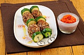 Hackfleisch with courgette in skewers in serving dish with red pepper dip