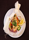 Herb salmon with vegetables in parchment cloth on plate