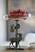 Cherries on old cake stand made of cast iron with reh figurine