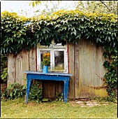alter blauer Tisch vor Holzhütte Holzhaus, Fenster, verwittert