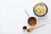 Ribbon pasta and Bolognese sauce in pan on white background
