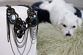 Close-up of jewellery on sofa arm with white dog on fur carpet in background
