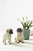 Grape hyacinth in white vase with two porcelain pugs figurine