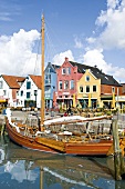 View of colourful gabled houses in centre of historic sail boat at wharf in Husum, Germany