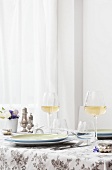 Frühlingshafte Tischdeko, zwei Weißweingläser, gedeckter Tisch