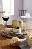 Cheese, baguette, wine, and glass cloche on wooden table