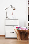 White drawer chest with lamp and vase on white wall