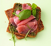 Pesto bread with ham and basil on green background