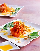 Ginger carrot salad with kumquat oil, peanuts and coriander on plate
