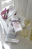 Rolled white cloth napkin with stamped designs and wine glasses on side