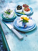 Three different dishes of goat cheese garnished with flowers and berries on plate
