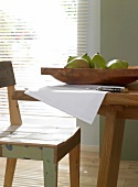 Close-up of tables and chairs with wooden bowl of pears