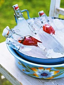 Bottles of sour cherry, citrus and mint syrup in bowl with crushed ice in summer kitchen