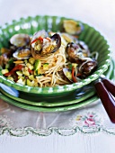 Spaghetti served with clams and courgettes in green bowl in summer kitchen
