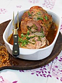 Roast beef with herbs and fennel sauce in baking dish in summer kitchen