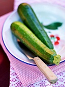 Close-up of two zucchini with knife on plate