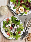Goat cheese salad and Greek salad on plates, overhead view