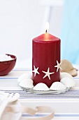 Close-up of red lit candle decorated with small starfish