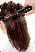 Close-up woman getting her hair straightened with hair straightening machine