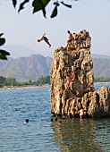 Tourists jumping into water from rocks at Bay of Olympos, Antalya, Turkey