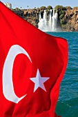 Close-up of Turkish flag in front of Duden Waterfall at Lara rocks in Antalya, Turkey