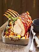 Pork roast garnished with herbs in baking dish, France
