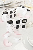 Disposable cameras with paper cover and heart shaped paper on table