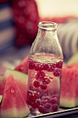 Mineral water with redcurrants in bottle and water melon