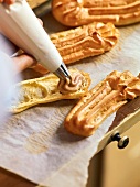Cream being filled in eclair with icing bag, France