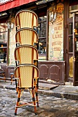 Frankreich, Vier übereinander gestapelte Stühle vor einem Bistro